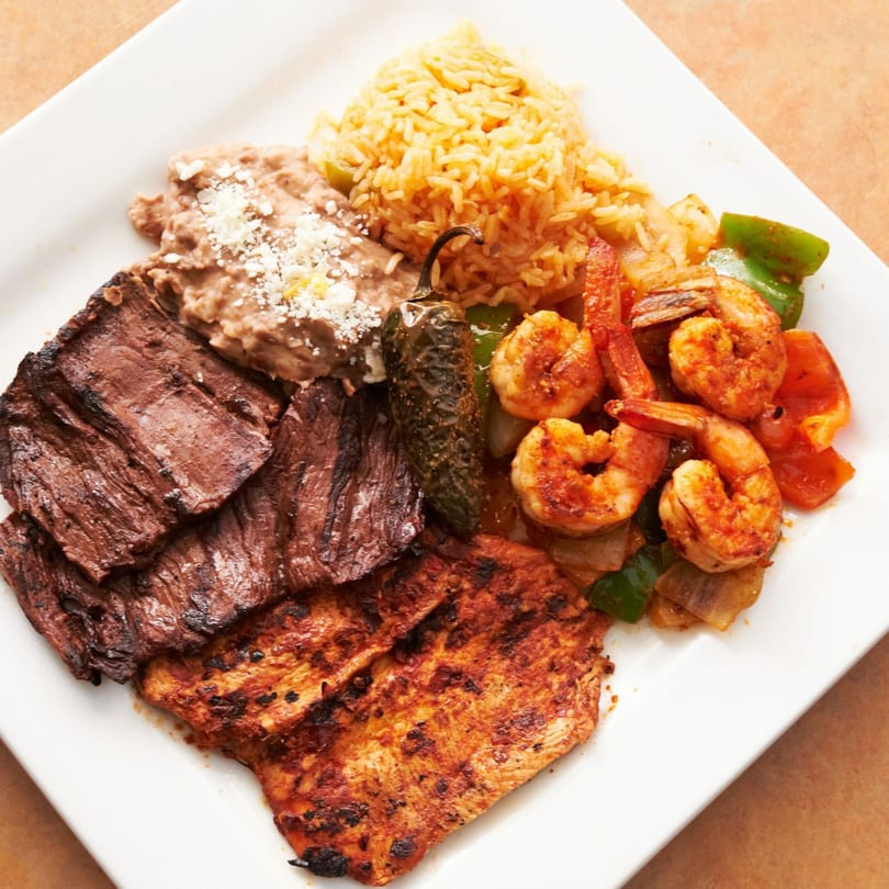 Acapulcos Mexican combo plate with grilled steak, chicken, shrimp, rice, refried beans, and a jalapeño.
